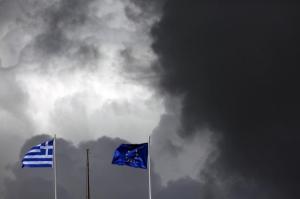 A European Union flag and a Greek national flag flutter atop a building in central Athens