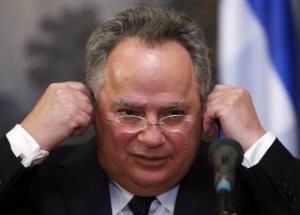 Greek Foreign Minister Kotzias adjusts his earphones during a news conference after a meeting with his Russian counterpart Lavrov in Moscow