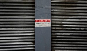A "For Rent" sign sits on the corrugated metal shutters of a closed down store at Modiano market in Thessaloniki, Greece, on Monday, May 11, 2015. Greece's new leadership needs to retreat from some of its anti-austerity demands to placate European governments and the International Monetary Fund after aid packages of 240 billion euros ($268 billion) since 2010 failed to turn the economy around. Photographer: Konstantinos Tsakalidis/Bloomberg