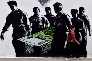 TOPSHOTS A young woman walks past a graffiti called 'Death of Euro' by French street artist Goin, in central Athens on June 19, 2015. The European Central Bank's decision-making governing council will hold an emergency session on June 19 to discuss a request from the Bank of Greece for an increase in liquidity to Greek banks. AFP PHOTO / ARIS MESSINIS