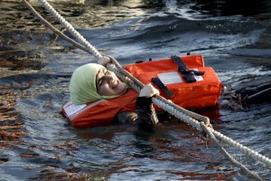 A refugee woman hangs on a rope as a half-sunken catamaran carrying around 150 refugees, most of them Syrians, arrives after crossing part of the Aegean sea from Turkey, on the Greek island of Lesbos, October 30, 2015. There were no casaulties amongst the refugees who were travelling on the catamaran, according to a Reuters witness. The death toll from drownings at sea has mounted recently as weather in the Aegean has taken a turn for the worse, turning wind-whipped sea corridors into deadly passages for thousands of refugees crossing from Turkey to Greece.  REUTERS/Giorgos Moutafis